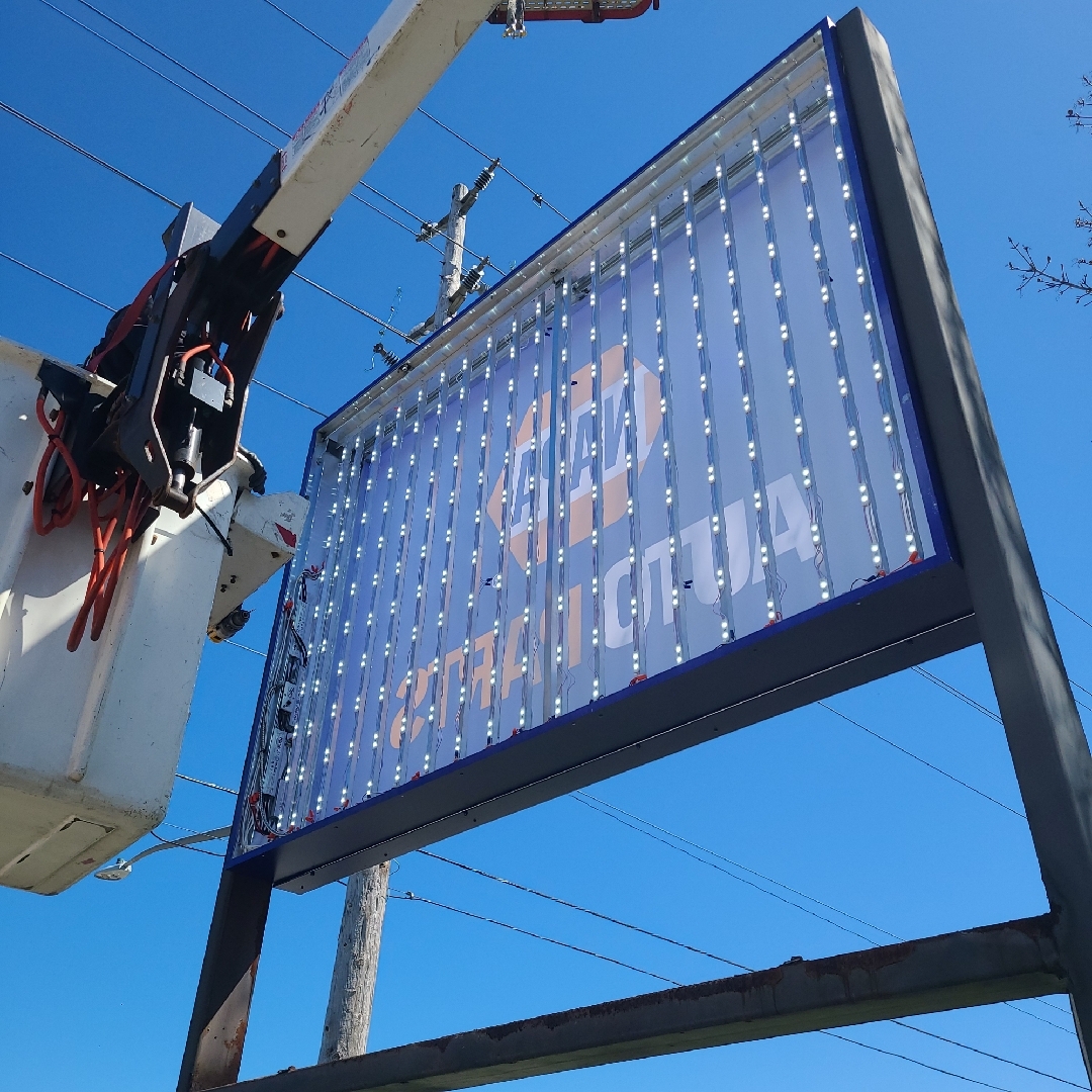 The inside of the Napa Auto parts pylon sign with a Yesco technician beside it in a bucket truck